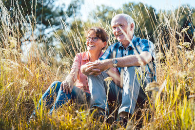 Senior couple sitting on grass in field