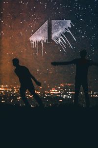 Silhouette people standing by illuminated city against sky at night