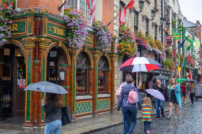 People on wet street in city during rainy season