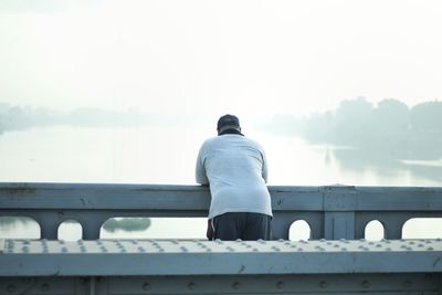 Rear view of man standing on bridge against sky