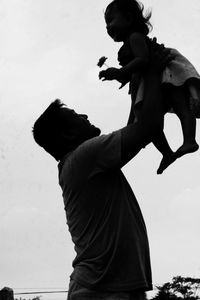 Low angle view of boy standing against sky