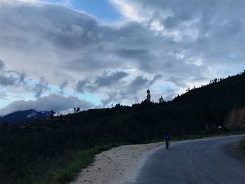 Man on road amidst trees against sky