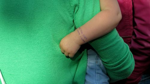 Midsection of mother carrying son with text on his hand