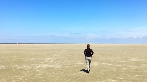 Rear view of man walking on desert against sky