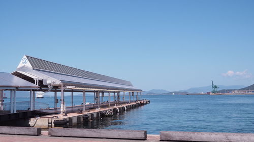 Built structure by sea against clear blue sky