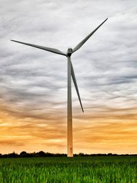 Windmill on field against sky during sunset