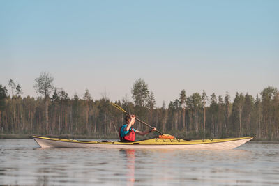 Man rowing boat in lake against sky