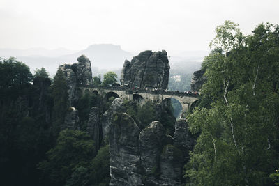 Bridge over rock formation against sky