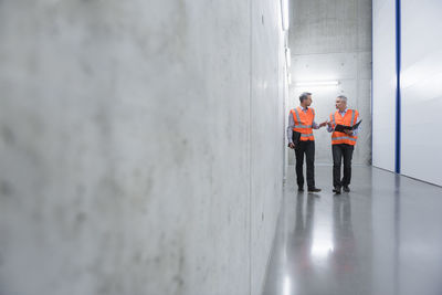 Two colleagues wearing safety vests talking