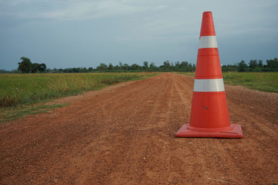 Road sign on field against sky