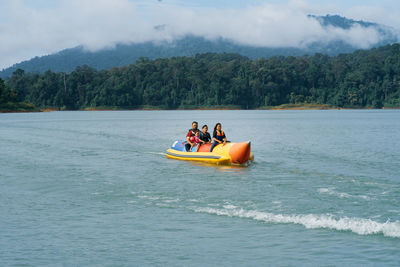 People on boat in water against sky