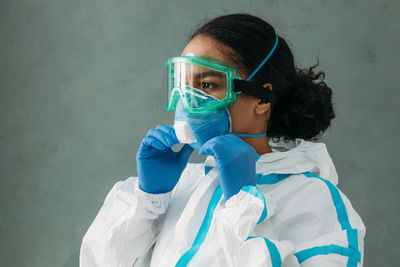 Close-up of doctor wearing mask standing against wall