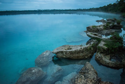 Scenic view of rocks by lake against sky