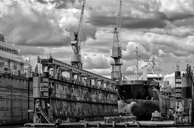 Cranes at construction site against cloudy sky