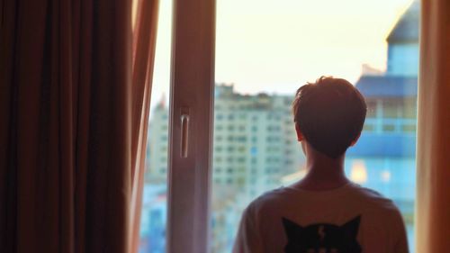 Portrait of young woman standing against window