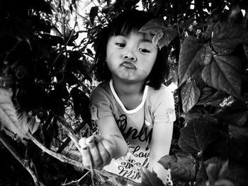 High angle view of cute girl making a face while standing by trees