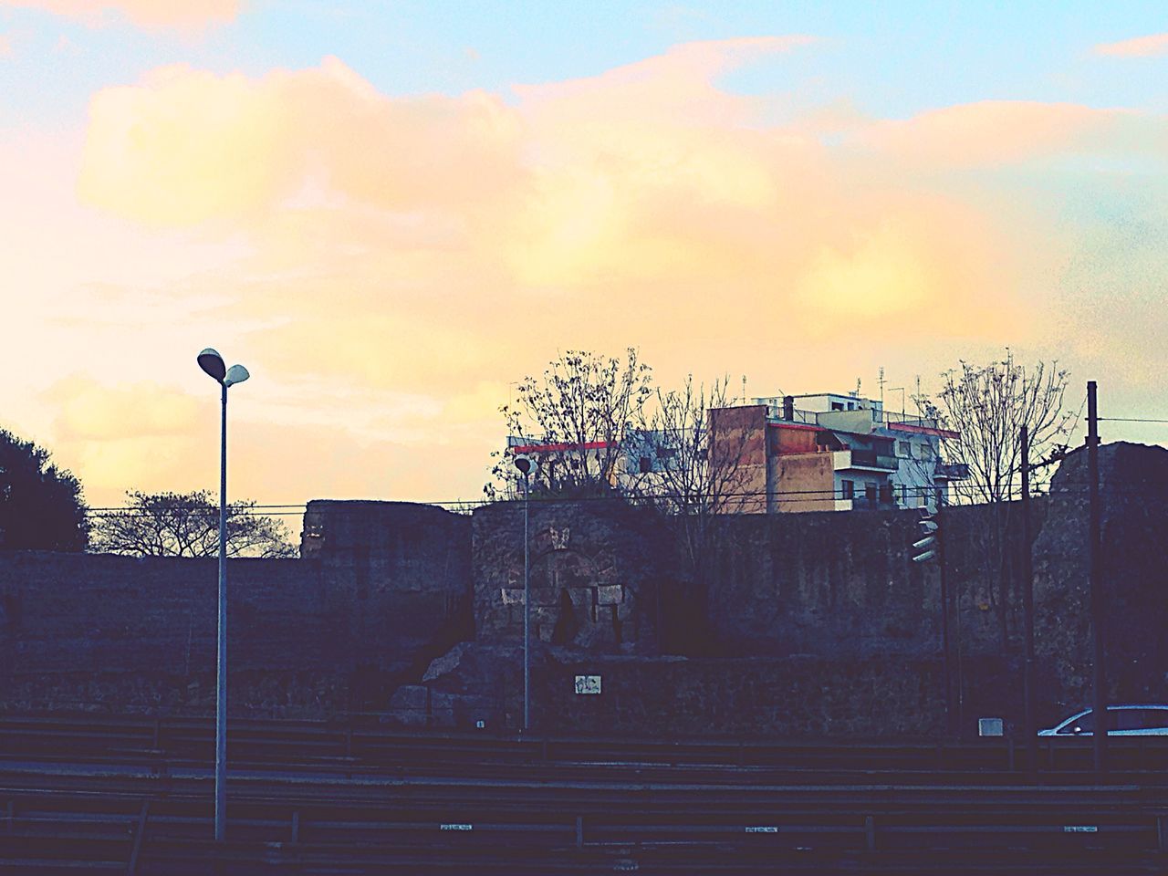 building exterior, architecture, sky, built structure, sunset, street light, house, cloud - sky, low angle view, orange color, silhouette, residential structure, lighting equipment, residential building, tree, outdoors, railing, no people, dusk, nature