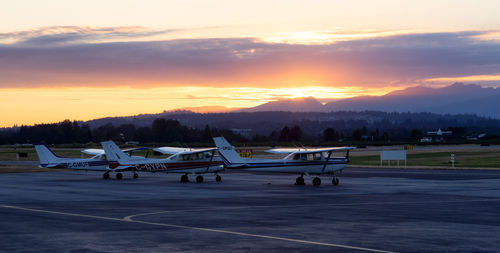 Airplane on airport runway against sky during sunset