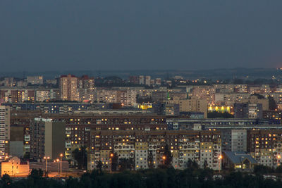 Illuminated buildings in city against clear sky at night