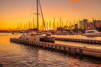 Sailboats in sea at sunset