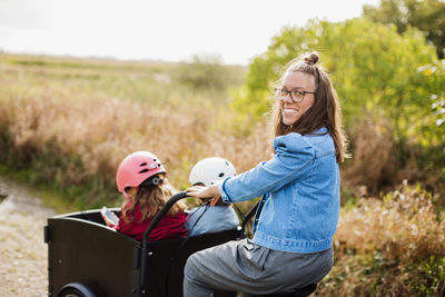 Mother pushing daughters in bicycle cart