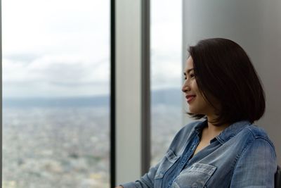 Portrait of young woman looking through window