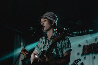 Musician singing while playing guitar on stage