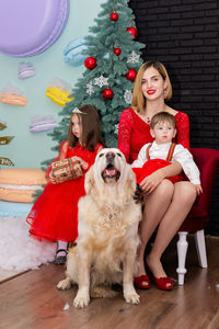 Portrait of young woman with dog sitting on floor at home