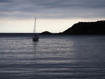 Sailboat sailing on sea against sky at sunset