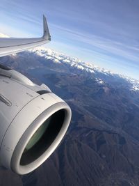 Airplane flying over snowcapped mountains against sky