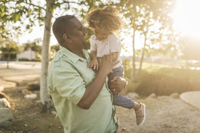 Happy father carrying son while standing at park