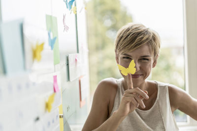 Smiling businesswoman with adhesive notes at whiteboard in modern office