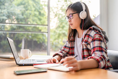 Midsection of woman using phone while sitting on table