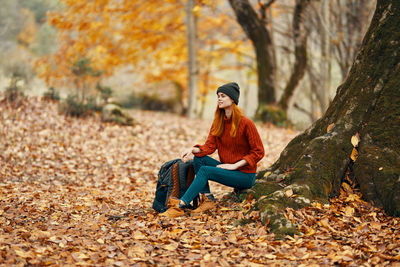 Young woman sitting on leaves during autumn