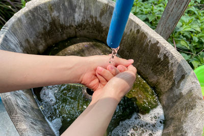 Woman washing her hands with water outdoor at a public faucet