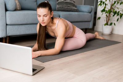 Young brunette woman doing streaming online yoga. female practicing virtual yoga from laptop at home