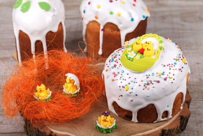 Easter cake on a wooden stand, decorated with colored dragees, with sweet decorative figures 