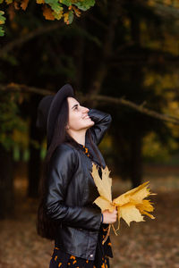 Portrait of young woman standing against tree