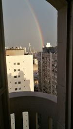 Rainbow over buildings in city against sky