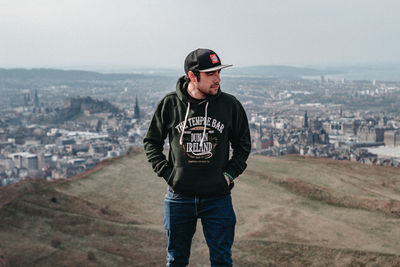 Portrait of man standing in city against sky