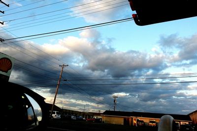 Low angle view of power lines against cloudy sky