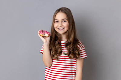 Portrait of young woman holding apple against gray background