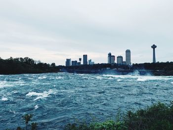 Sea and buildings in city against sky