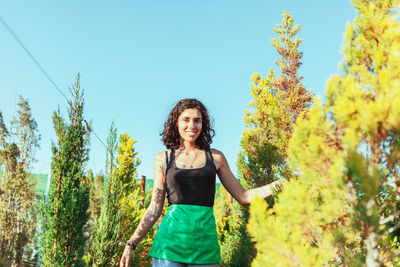 Portrait of smiling woman standing against plants