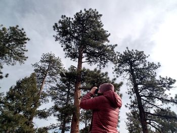 Rear view of man standing by tree against sky