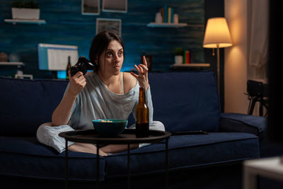 Young woman using mobile phone while sitting at home