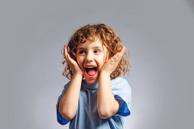 Portrait of smiling girl standing against gray background