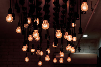 Low angle view of illuminated light bulbs hanging from ceiling