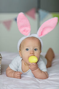 Close-up of cute baby boy lying on bed at home