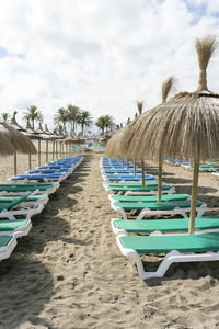 Empty chairs on beach against sky